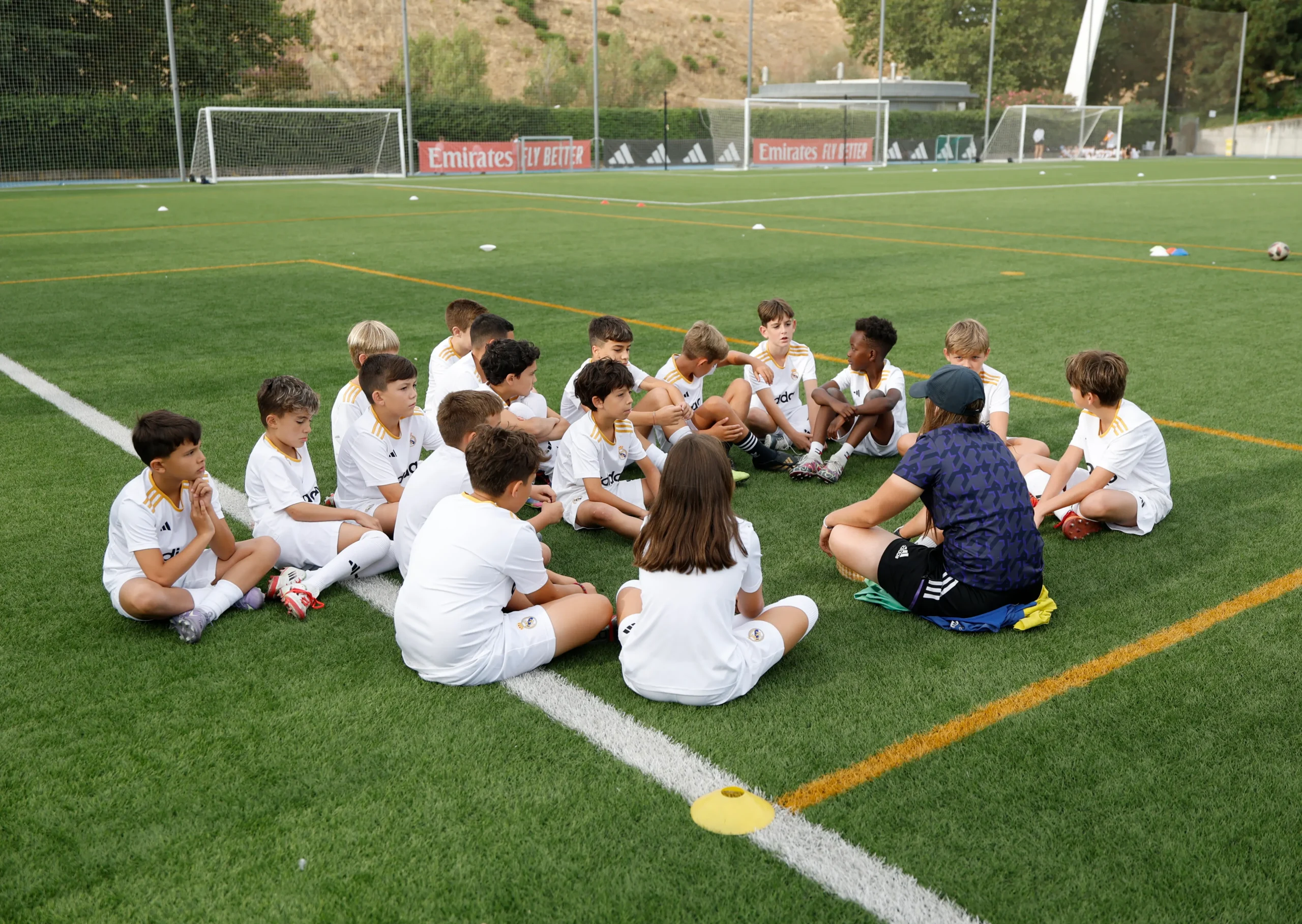 Niños/as y entrenador en el campus de fútbol de verano del Campus Experience Real Madrid Foundation.